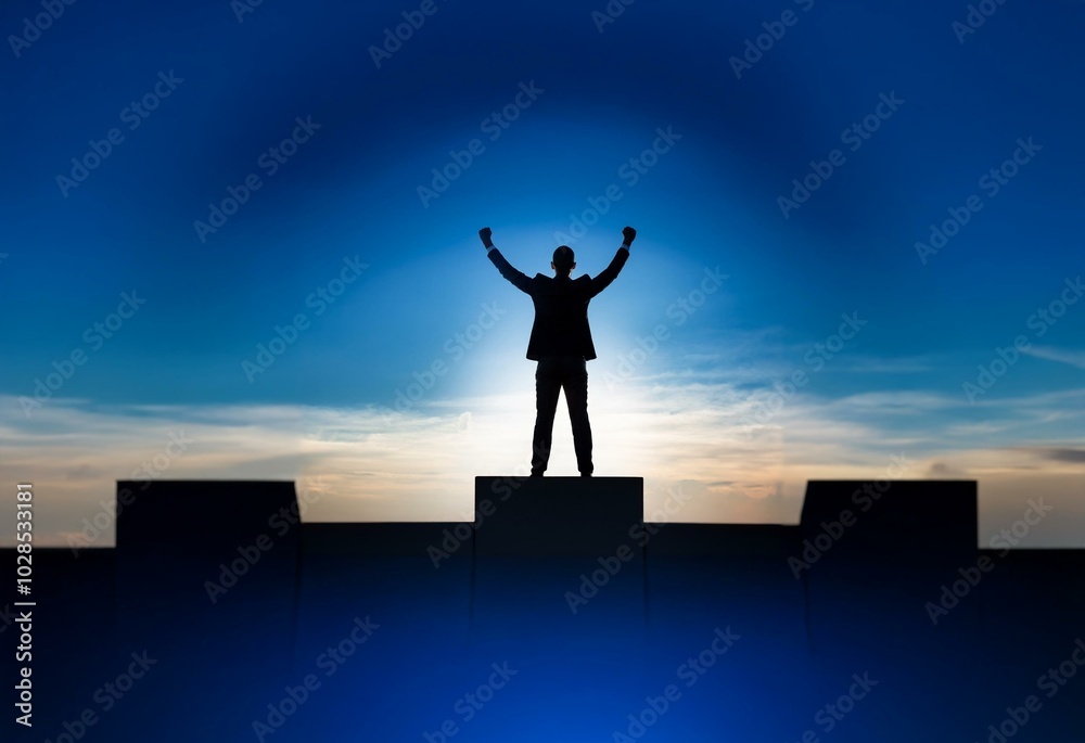 A businessman stands on a platform with his arms raised in victory against a blue sky with white clouds. A businessman stands on a platform with his arms raised in victory against a blue sky with white clouds.