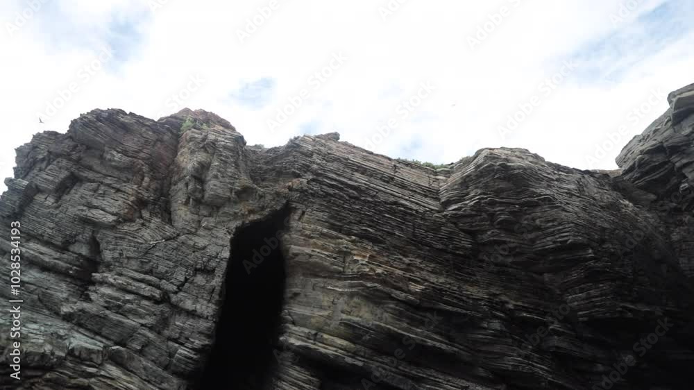 Dramatic cliffs with layers of textured rock formations beneath a cloudy sky Dramatic cliffs with layers of textured rock formations beneath a cloudy sky