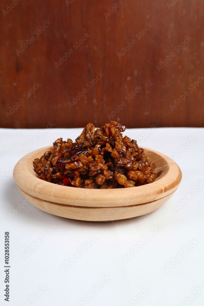 Stir-fried Tempe is a typical Indonesian dish with spices, garlic, shallots, chilies and soy sauce. served on a wooden plate Stir-fried Tempe is a typical Indonesian dish with spices, garlic, shallots, chilies and soy sauce. served on a wooden plate
