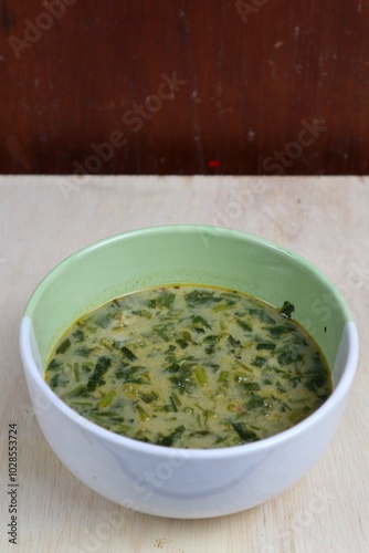 spinach leaf vegetable soup, traditional soup served in a bowl wood background