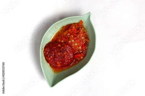 Traditional Indonesian chili sauce namely crushed chilies with shrimp paste, garlic, shallots and spices served in a bowl isolated on a white background photo