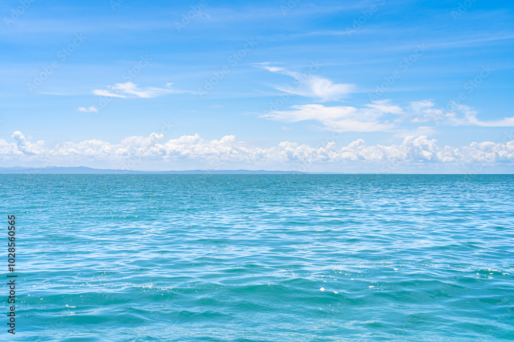 Serene sea ocean view with gentle waves, distant mountains, and a blue sky with clouds. Serene sea ocean view with gentle waves, distant mountains, and a blue sky with clouds.