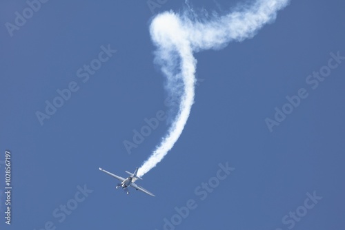 Fotografie Aerobatic plane performing stunt with smoke trail
