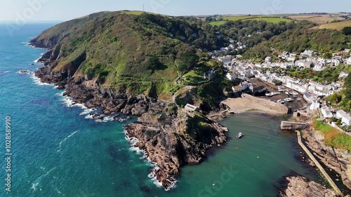 Aerial view over the coastal Polperro village, with seafront houses on a cliff surrounded by nature
