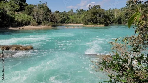 Static shot of the Xanil River surrounded by a forest on a sunny day in Chiapas, Mexico photo