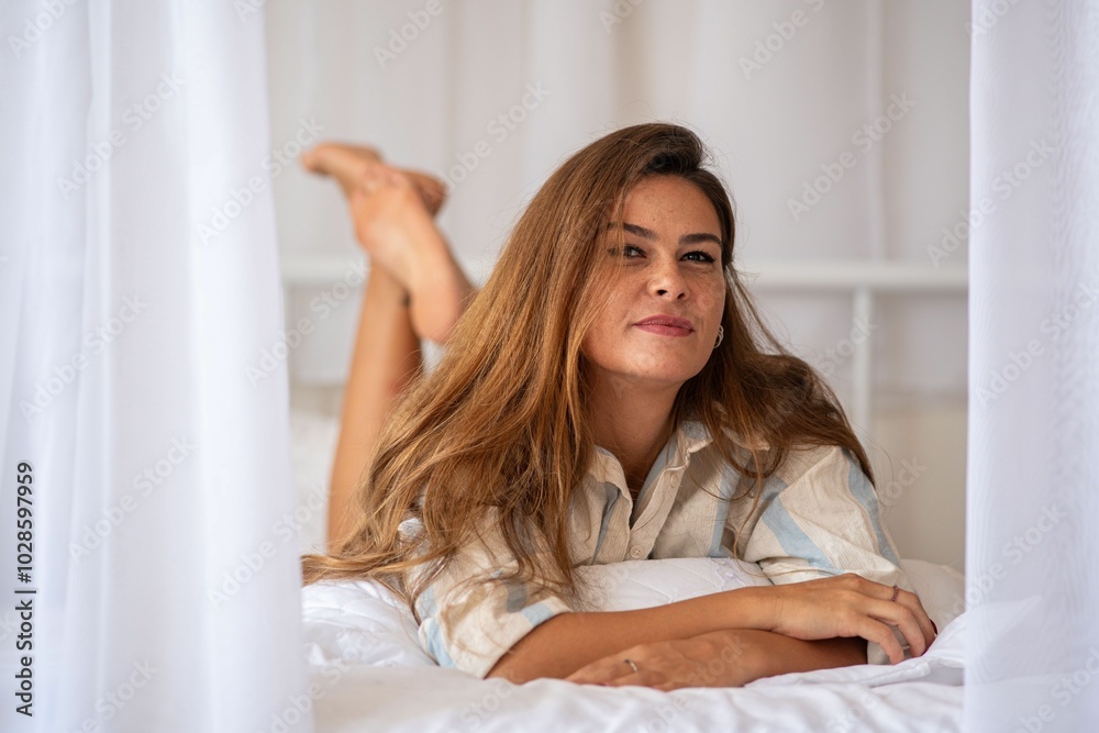 Young woman relaxing on a bed in a cozy bedroom. Young woman relaxing on a bed in a cozy bedroom.