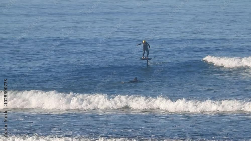 Foiling on ocean wave aerial view from behind on clear summer's day, Foiling on ocean wave aerial view from behind on clear summer's day,