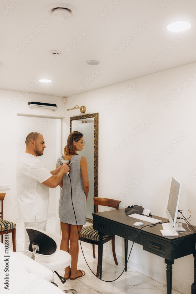 Fototapeta premium Male doctor examining mole on back of woman in clinic