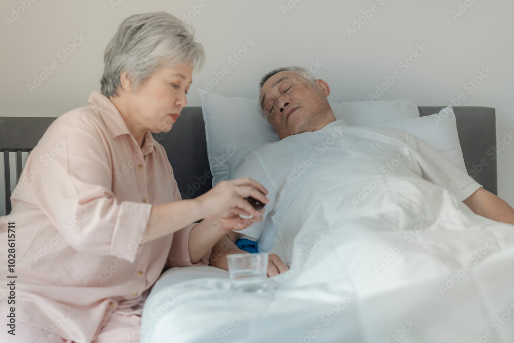 Fototapeta premium An elderly woman tends to her husband by administering medication while he rests in bed. The image emphasizes caregiving, compassion, and elderly support in a peaceful home setting.