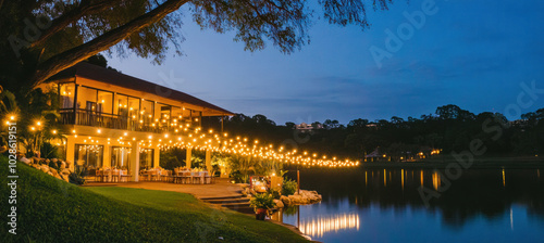 Outdoor wedding reception venue by a lake at dusk, decorated with string lights