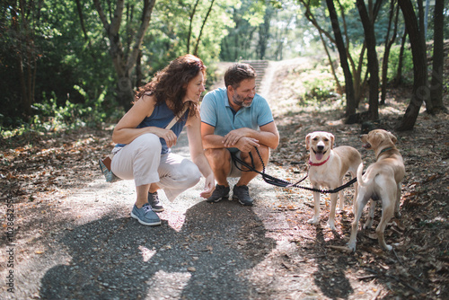 Canvas Print Mature couple enjoys a time together with dogs in the park
