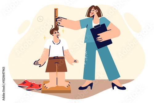 Woman pediatrician measures height of little boy and smiles, enjoying work in children clinic
