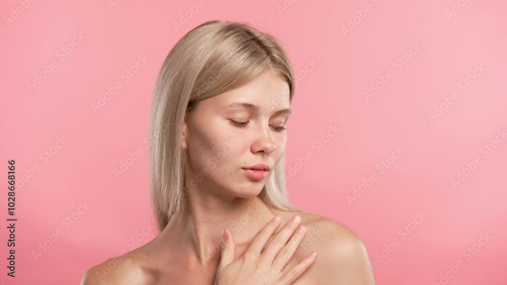 Young blonde woman posing at camera, touches neck and collarbone smooth skin, isolated on pink studio background. Beauty skin care concept Young blonde woman posing at camera, touches neck and collarbone smooth skin, isolated on pink studio background. Beauty skin care concept
