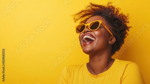 A vibrant woman wearing yellow glasses and t-shirt laughs exuberantly against a bright background, capturing a moment of pure joy and stylish exuberance. photo