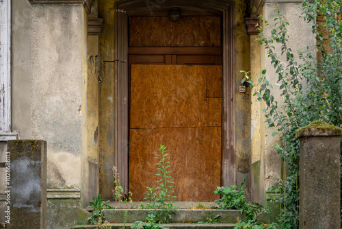 door blocked with fiberboard in an old abandoned tenement house in the city center photo