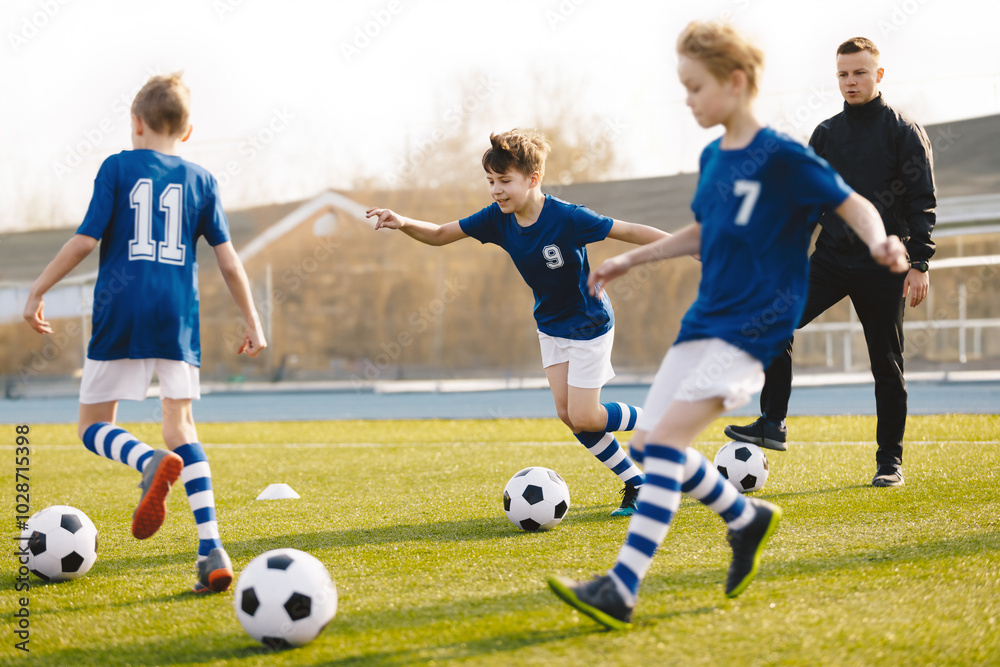 Football Training for School Boys. Physical Education Class for Children. Young Coach With Kids in Team on Training Unit. Youth Team Coach Training School Boys in Football Soccer Football Training for School Boys. Physical Education Class for Children. Young Coach With Kids in Team on Training Unit. Youth Team Coach Training School Boys in Football Soccer