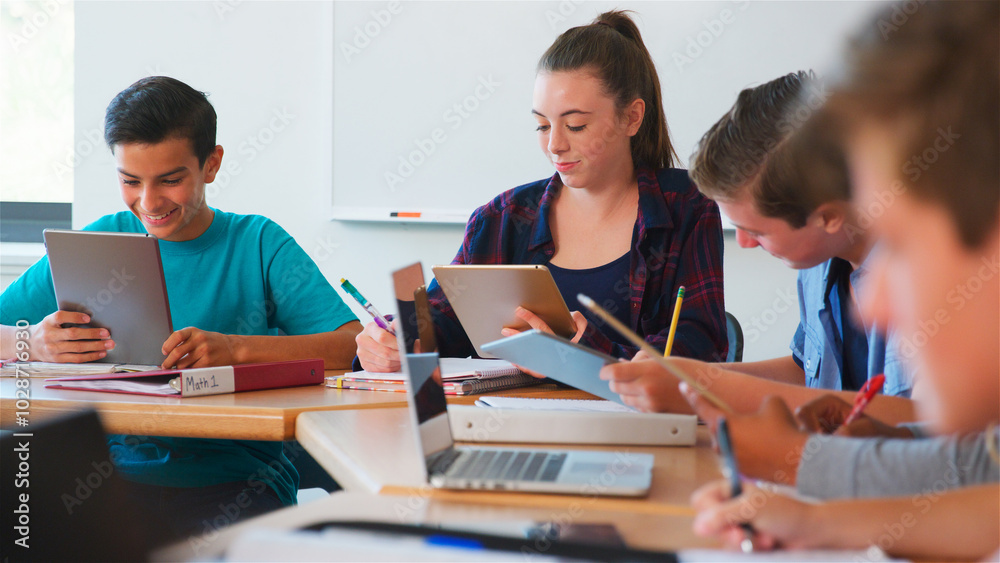 Class Of Multi-Cultural High School Pupils Using Digital Devices Working At Desks Class Of Multi-Cultural High School Pupils Using Digital Devices Working At Desks