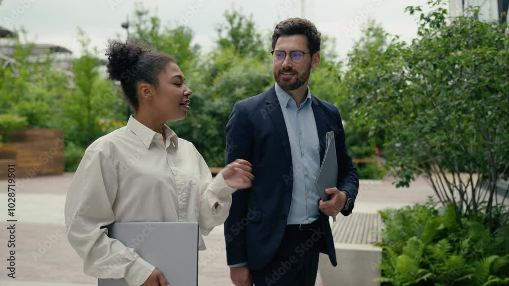 Multiracial business people walking in city multiethnic colleagues Caucasian businessman man male guy African woman businesswoman girl female talking walk conversation go to office hold laptop folder