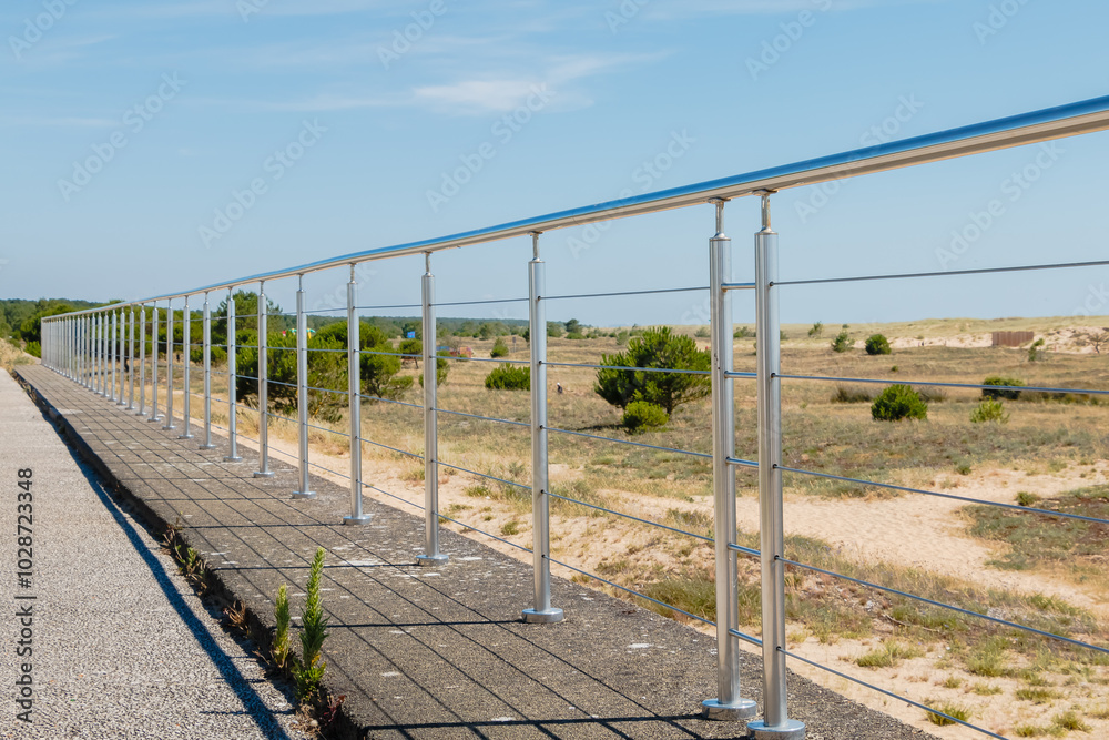 Metal barrier in front of a sand dune on a beautiful summer day