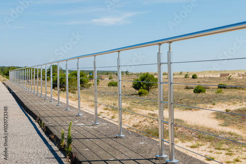 Obraz na płótnie Metal barrier in front of a sand dune on a beautiful summer day w salonie