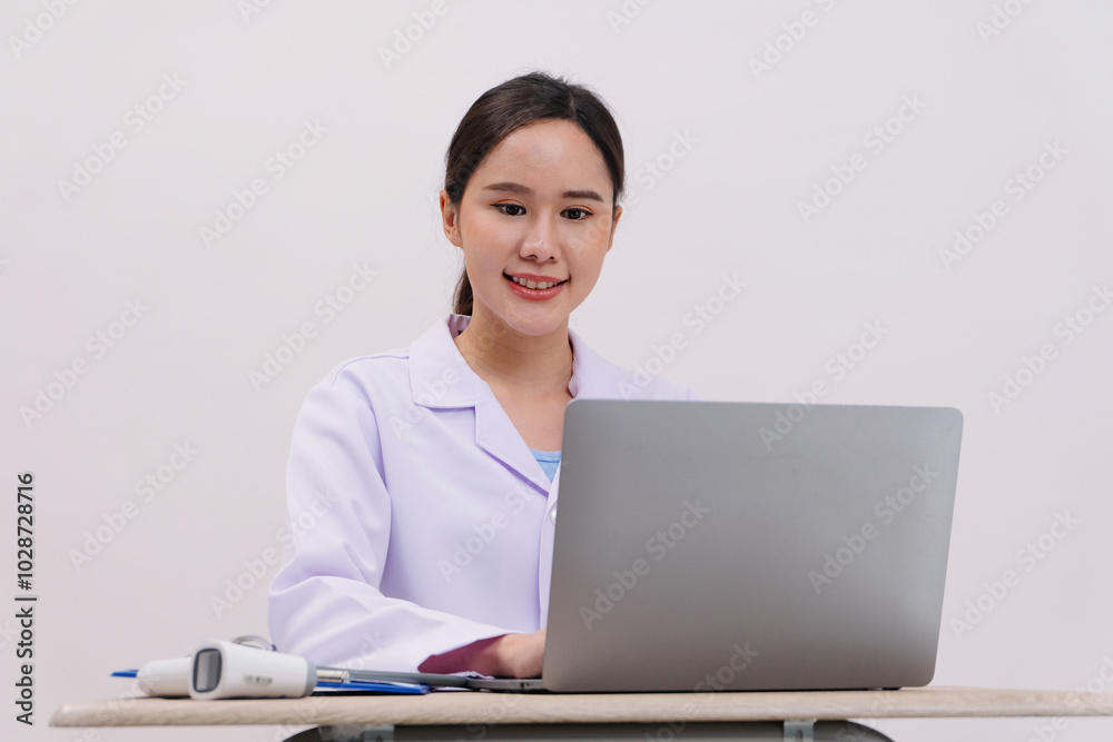 Asian female doctor sitting and working with laptop, white background. Asian female doctor sitting and working with laptop, white background.