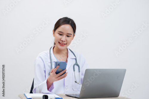 Asian female doctor sitting and working with laptop, white background.