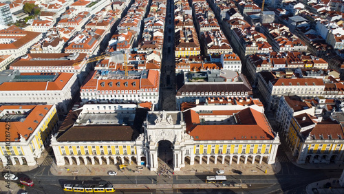 Uma imagem icónica do Terreiro do Paço (também conhecido como Praça do Comércio), situada na Baixa Pombalina, em Lisboa. A ampla praça está rodeada por majestosos edifícios de cor amarela com arcadas  photo
