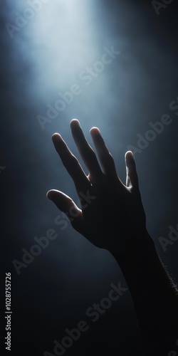 A hand is raised in the air, with the fingers spread out. The image has a spiritual or religious feel to it, as if the hand is reaching towards something higher