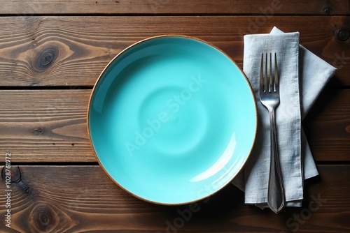 Light blue ceramic plate with a neatly folded gray napkin and cutlery set on a rustic wooden table.