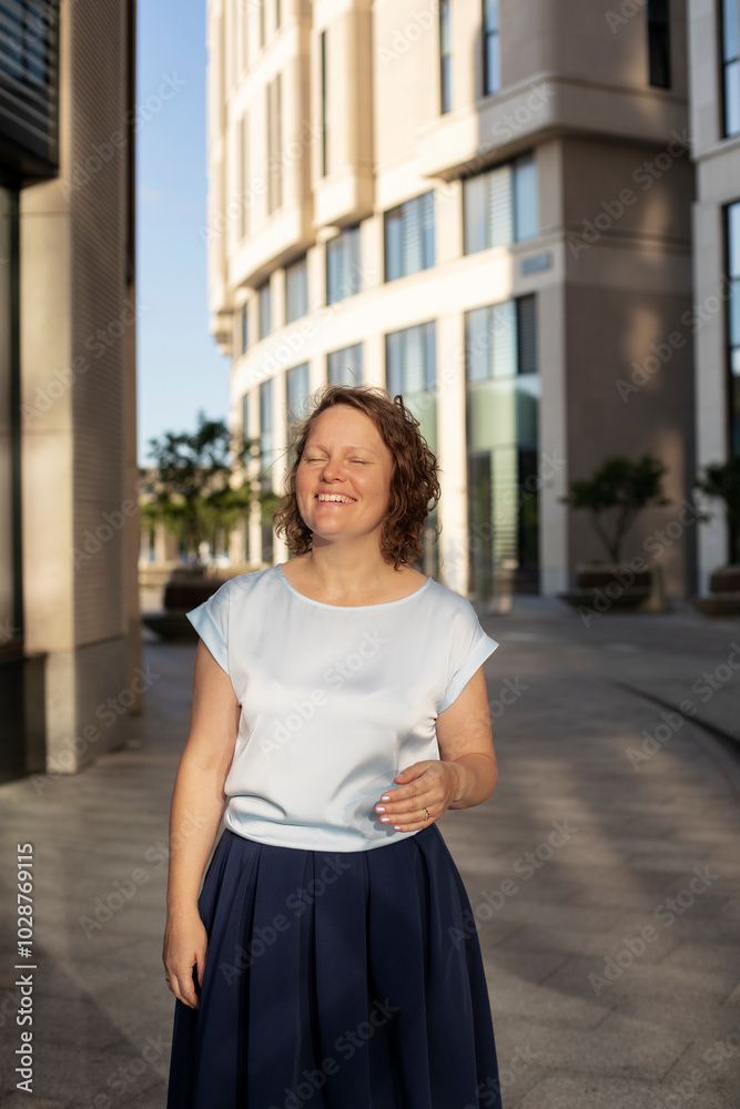 Fototapeta premium woman with curly short hair smiles and looks at the camera, close-up, half-length portrait in the city of a woman 40-45 years old 