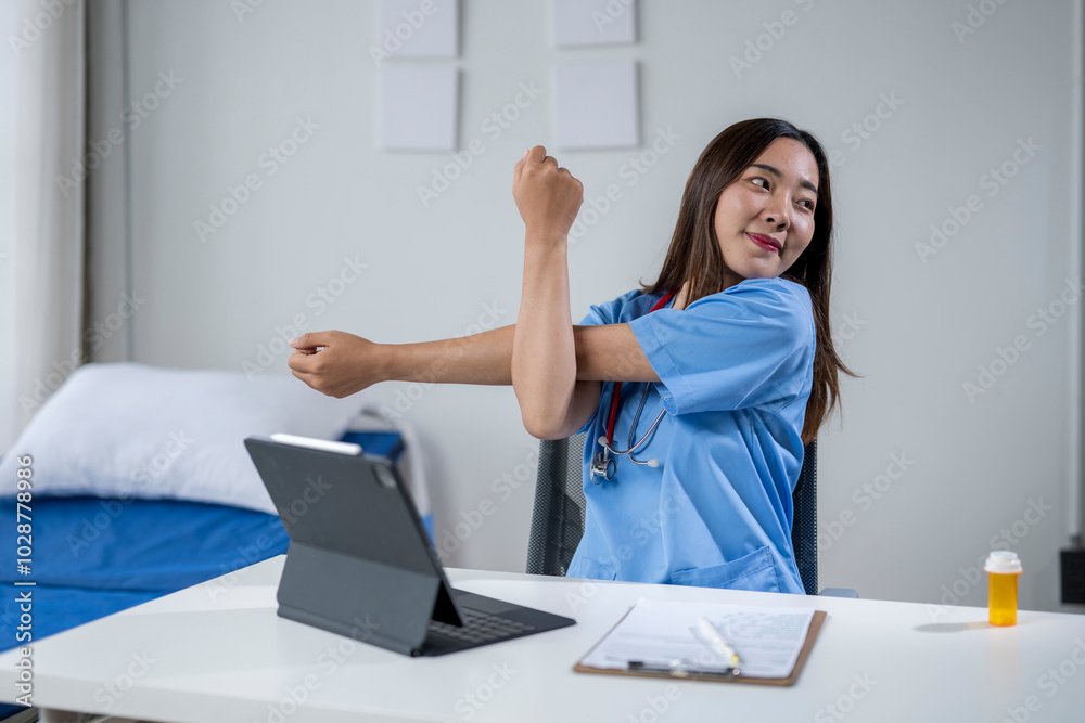 Asian female doctor stretching her arms at her desk in the hospital office Asian female doctor stretching her arms at her desk in the hospital office