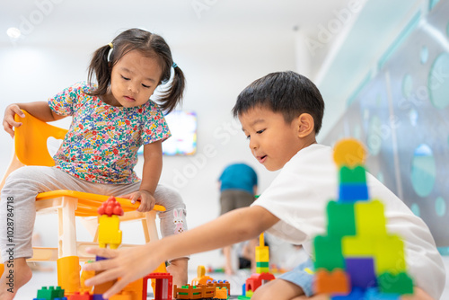 Adorable little child boy and girl enjoying play colorful plastic toy block building