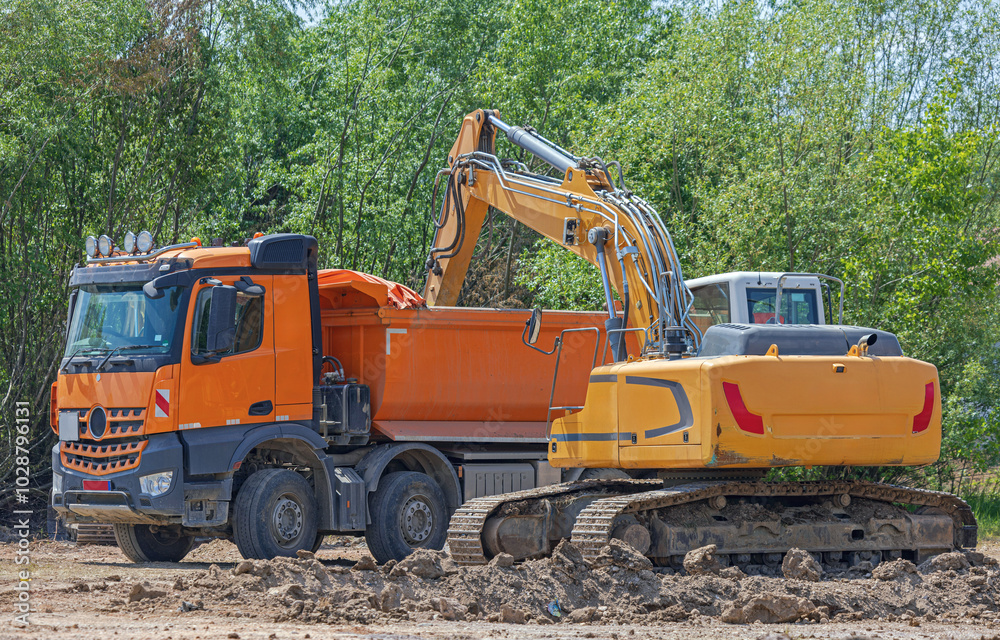 Excavator Digger Loading Dirt in Tipper Truck at Construction Site Excavator Digger Loading Dirt in Tipper Truck at Construction Site