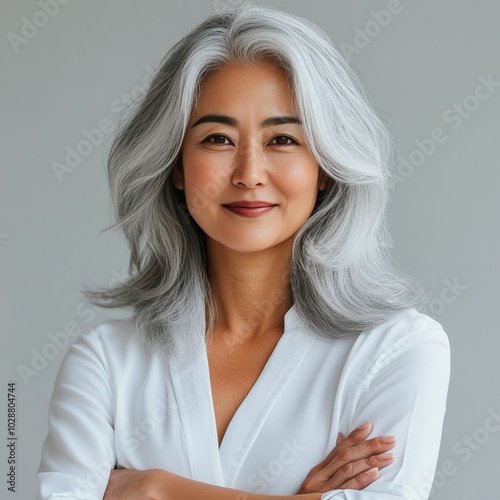 Elegant woman with silver hair poses confidently in modern studio setting dur...