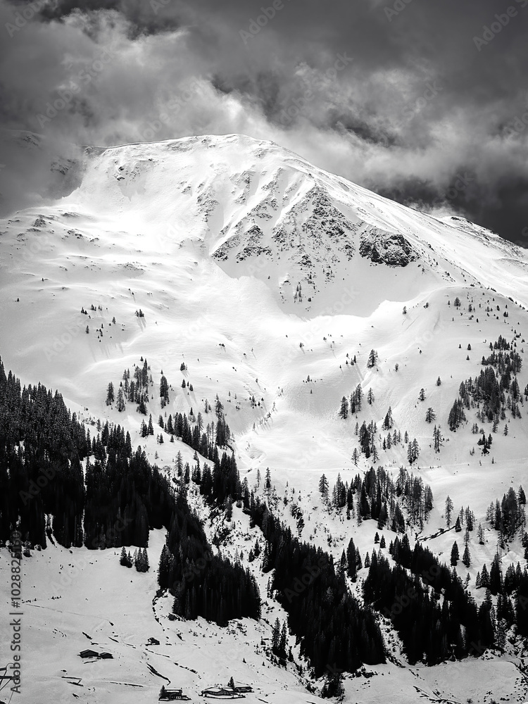 Scenic view of snow covered mountain in the ski region of Saalbach-Hinterglemm in the Austrian alps against cloudy sky in black and white