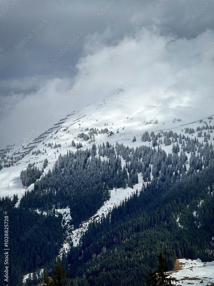 Scenic view of snow covered mountain and snow line in the ski region of Saalbach-Hinterglemm in the Austrian alps against cloudy sky