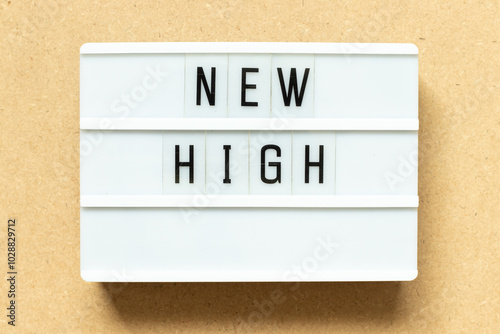 Lightbox with word new high on wood background