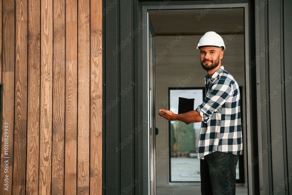 Showing the wooden house that is under construction. Industrial worker in warehouse Showing the wooden house that is under construction. Industrial worker in warehouse