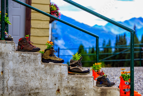 Banff, Rocky Mountain National Park, Alberta, Canada - August 23, 2019: Flowers potted on hiking boots are lined up on the stairs. photo