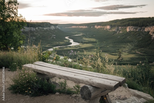 A bench sits on a hill overlooking a river photo