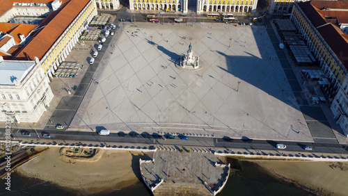 Uma imagem icónica do Terreiro do Paço (também conhecido como Praça do Comércio), situada na Baixa Pombalina, em Lisboa. A ampla praça está rodeada por majestosos edifícios de cor amarela com arcadas  photo