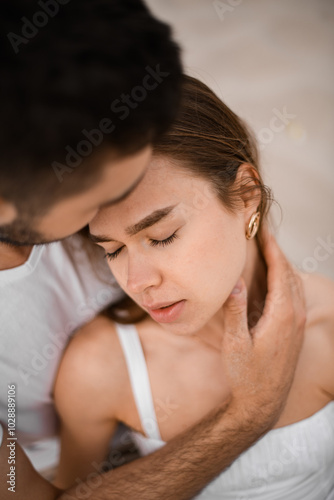 Bride closes her eyes and leans her head on man's shoulder, and the man gently hugs her neck with his palm