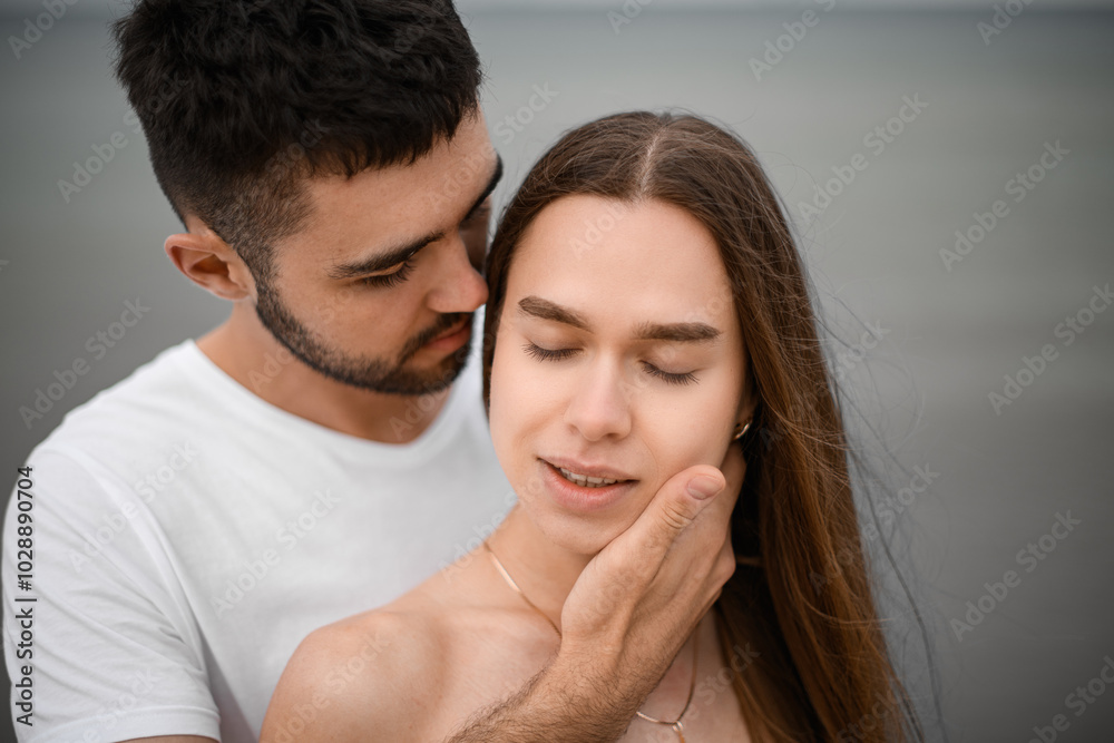 Close-up of the faces of a man and a woman in love. A man stands behind a woman and caresses her face with his hand Close-up of the faces of a man and a woman in love. A man stands behind a woman and caresses her face with his hand