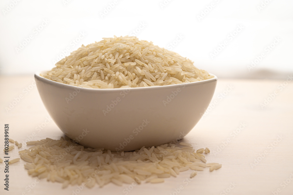 Raw basmati rice, in white bowl, on light wooden surface. Raw basmati rice, in white bowl, on light wooden surface.