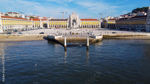 Uma imagem icónica do Terreiro do Paço (também conhecido como Praça do Comércio), situada na Baixa Pombalina, em Lisboa. A ampla praça está rodeada por majestosos edifícios de cor amarela com arcadas  photo