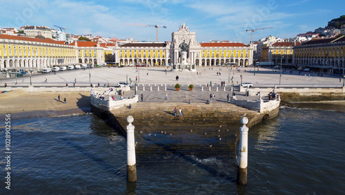 Uma imagem icónica do Terreiro do Paço (também conhecido como Praça do Comércio), situada na Baixa Pombalina, em Lisboa. A ampla praça está rodeada por majestosos edifícios de cor amarela com arcadas  photo