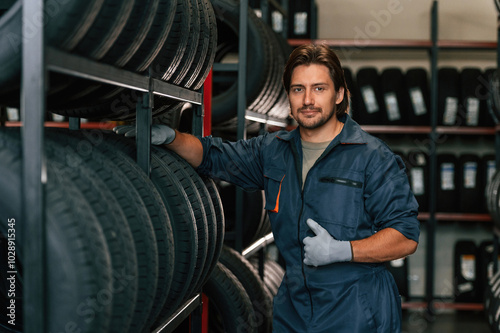 In professional uniform. Man is in the tire fitting car service