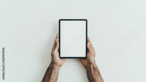 Man holding a tablet on solid grey background. Tablet mockup display for technology, website, landing page, app, ipad, social media, blog, advertisement. Blank white screen. 