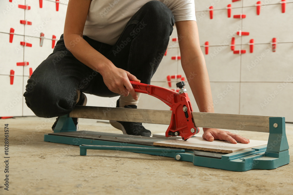 Cutingt tiles with a standard manual tile cutter. Process of installation of tiles in the bathroom step by step. DIY home improvement.
Cutingt tiles with a standard manual tile cutter. Process of installation of tiles in the bathroom step by step. DIY home improvement.