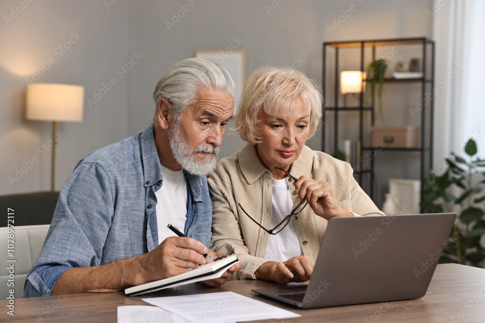 Pension savings. Senior couple planning budget at wooden table indoors Pension savings. Senior couple planning budget at wooden table indoors